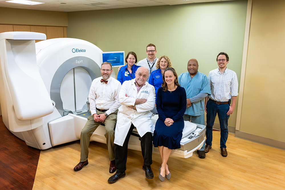 a group of doctors, nurses and techs pose around the Elekta Esprit Gamma Knife machine at MUSC Hollings Cancer Center
