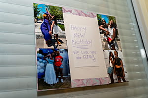 an encouraging poster featuring photos of the patient at graduation and other events is taped to the window in the hospital room