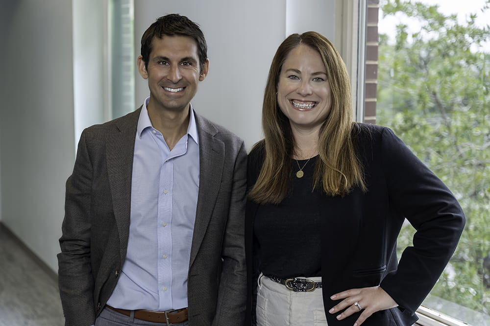 a man and woman in business casual pose in a hallway at Hollings Cancer Center