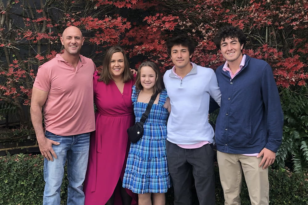 a family photo of a couple, a young girl and two older boys in a park