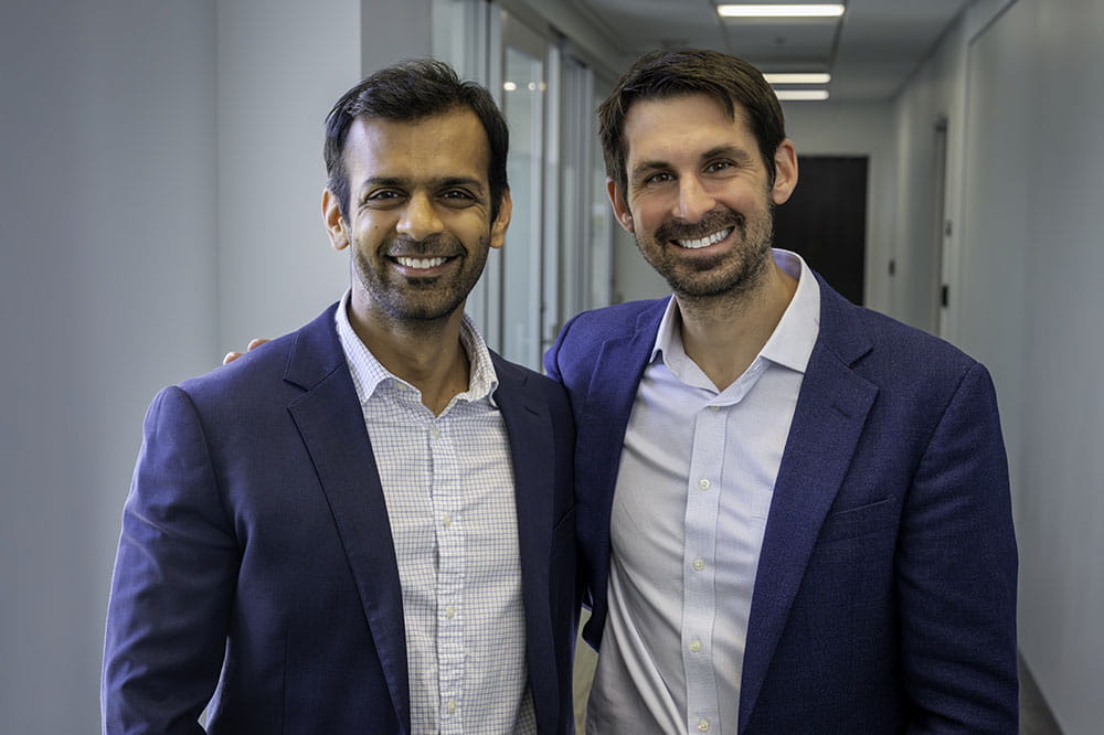 two researchers in blue sports coats and open collars pose together 