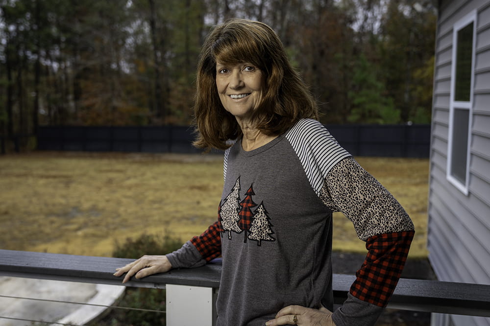 a woman poses on the back porch of her home