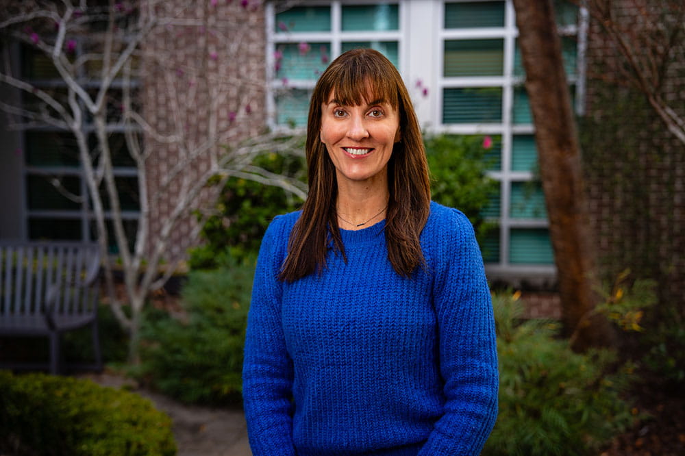 woman in blue, the awareness color for colorectal cancer, poses in a garden setting