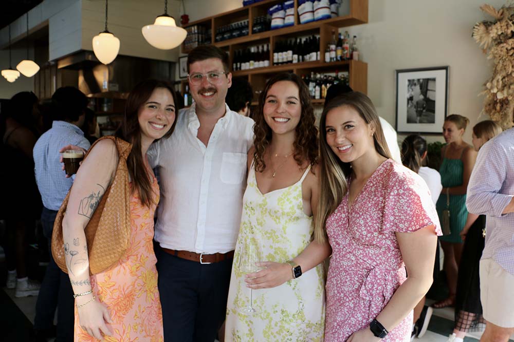 Three women and a man pose in a restaurant.
