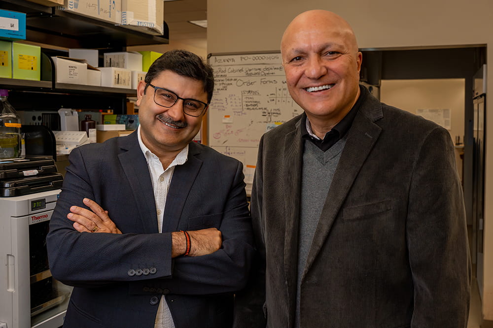 two men in business casual pose in a science lab