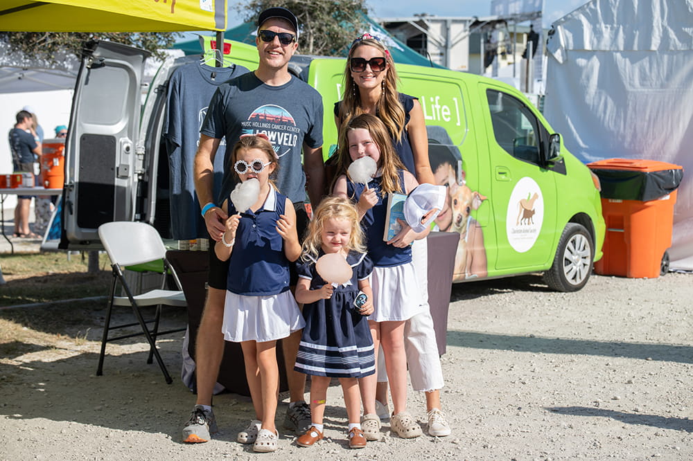 a couple with three young children pose at an outdoor event