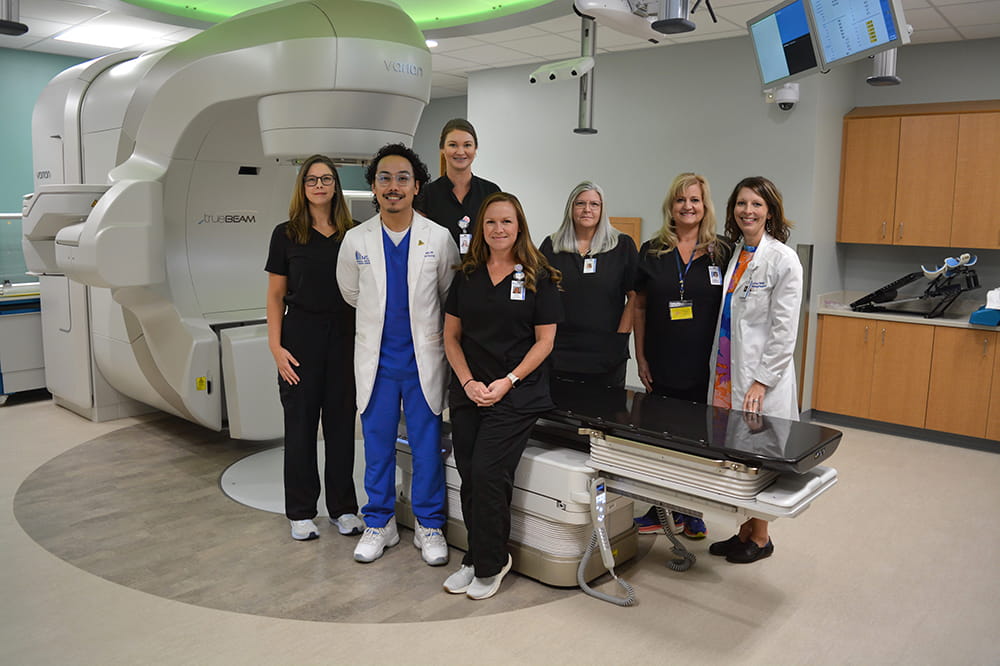 a group photo in front of a linear accelerator machine
