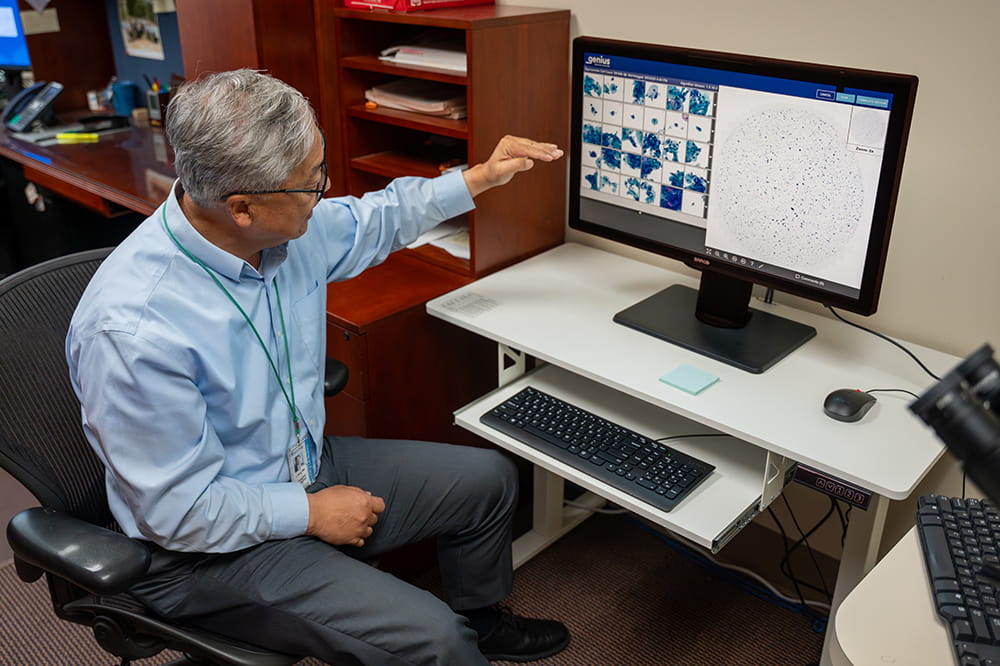 a man at a computer gestures toward the screen